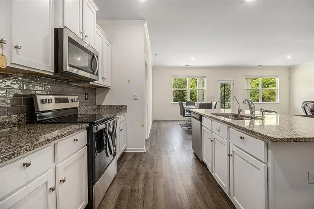 a kitchen with stainless steel appliances granite countertop wooden floors and granite counter tops