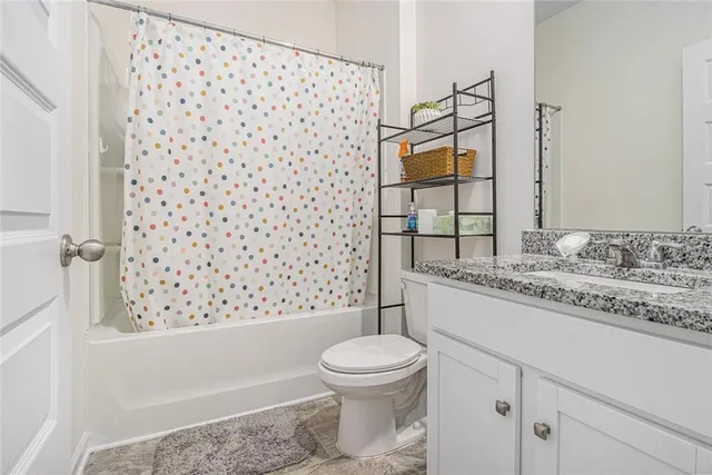 a bathroom with a granite countertop toilet a sink and a shower