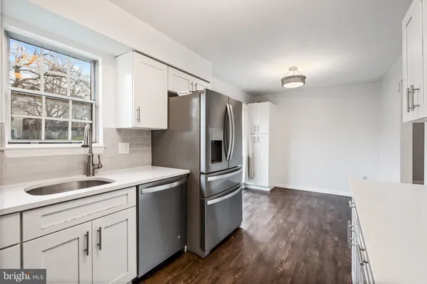 a kitchen with stainless steel appliances a refrigerator sink and wooden floor