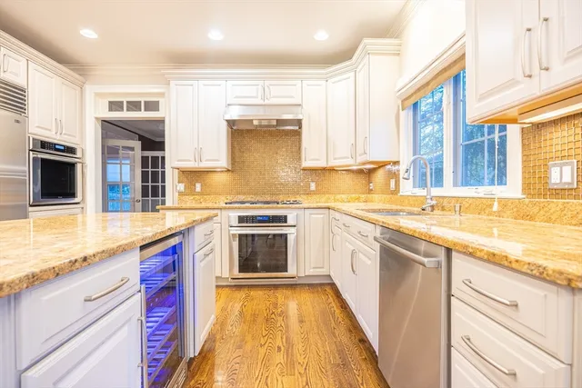 a large kitchen with kitchen island a large counter top and stainless steel appliances