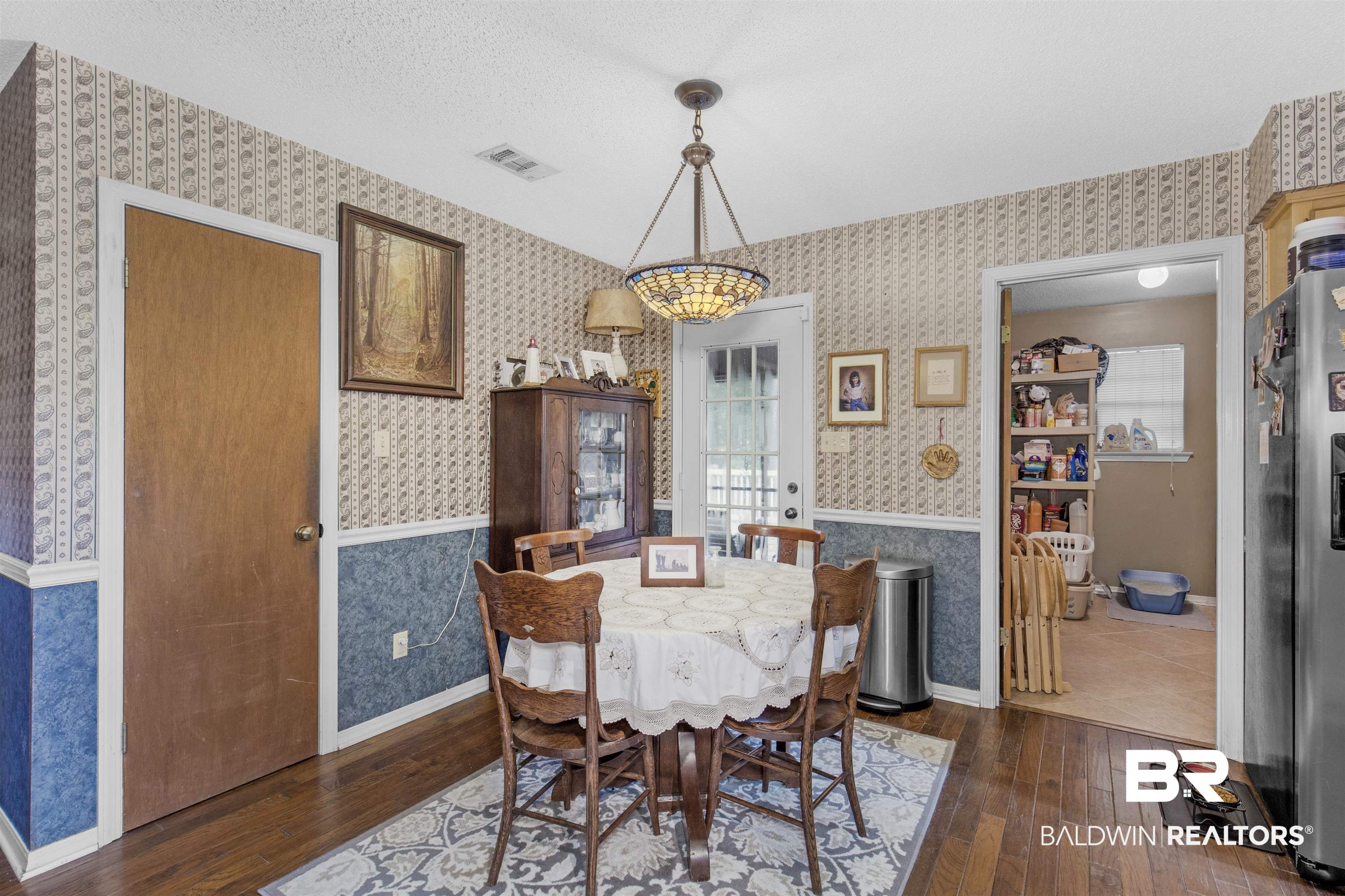 31375 Stagecoach Road Daphne, AL 36527 - Photo 10 of 21 Dining room featuring wallpapered walls, dark wood-style flooring, and baseboards