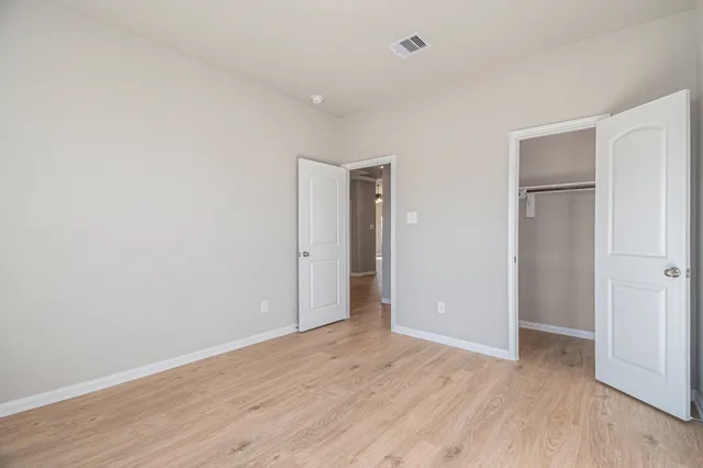a view of an empty room with wooden floor and closet