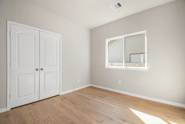 a view of an empty room with closet and a window