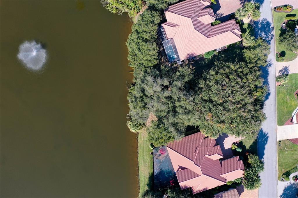 an aerial view of residential house with outdoor space and trees all around