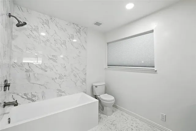 a bathroom with a white bath tub a toilet and a sink