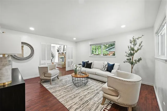 a living room with furniture a large window and wooden floor