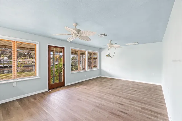 a view of an empty room with a window and wooden floor
