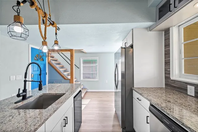 a kitchen with granite countertop a sink and a refrigerator