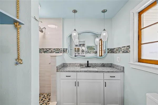 a bathroom with a granite countertop shower sink and mirror