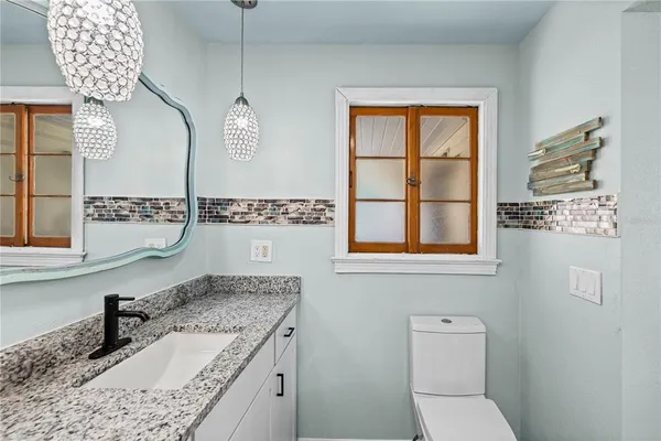 a bathroom with a granite countertop sink a toilet and a mirror