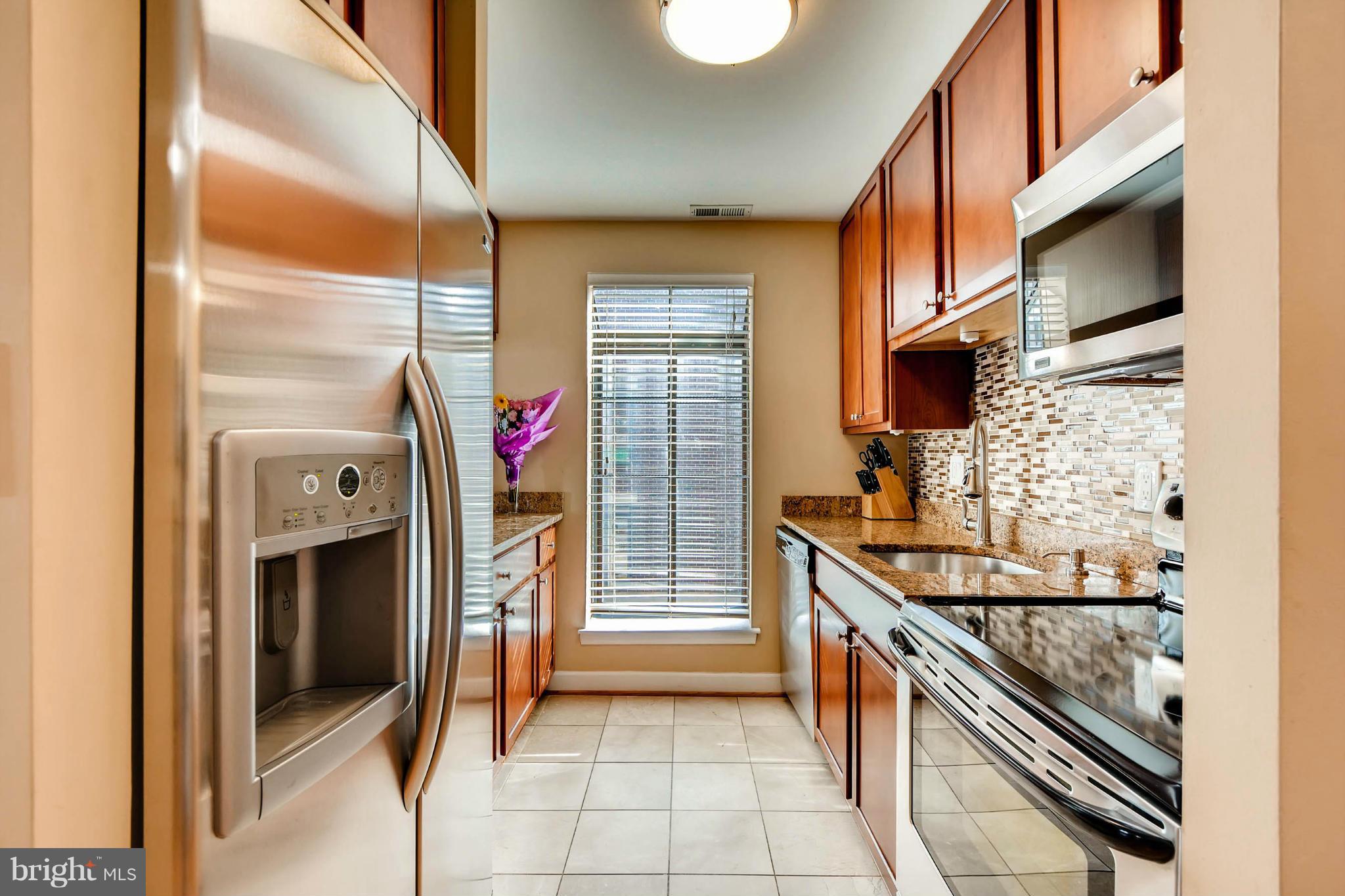 a kitchen with stainless steel appliances granite countertop a stove top oven a sink and a refrigerator