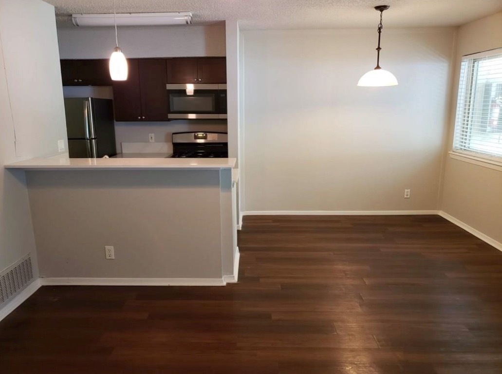 1202 Newning Avenue, Unit 113 Austin, TX 78704 - Photo 2 of 13 Kitchen featuring stainless steel microwave, freestanding refrigerator, dark wood-style floors, range, and a textured ceiling