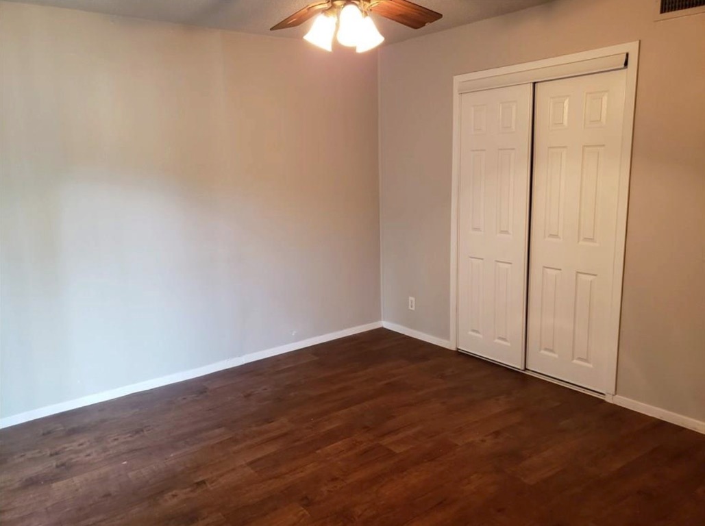 1202 Newning Avenue, Unit 113 Austin, TX 78704 - Photo 9 of 13 Unfurnished bedroom with dark wood-type flooring, a closet, and a ceiling fan