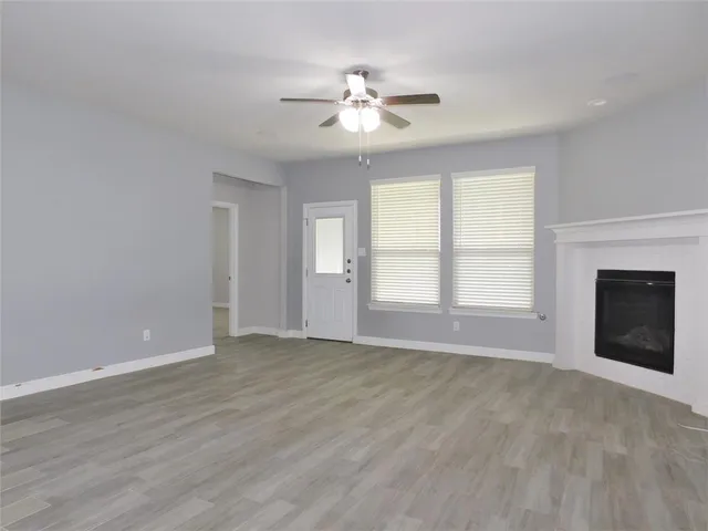 a view of an empty room with a window and a kitchen
