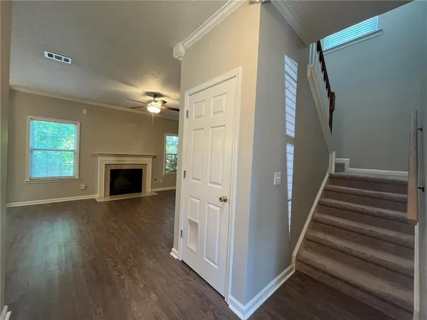 an empty room with wooden floor fireplace and windows
