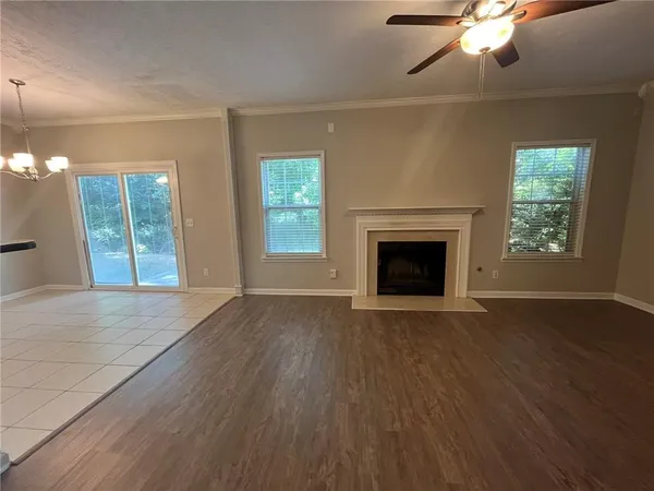 an empty room with wooden floor chandelier fan and windows