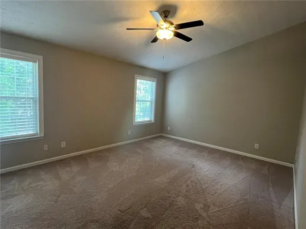 an empty room with chandelier fan and windows