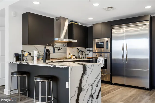 a kitchen with stainless steel appliances granite countertop a refrigerator a sink a stove and a refrigerator