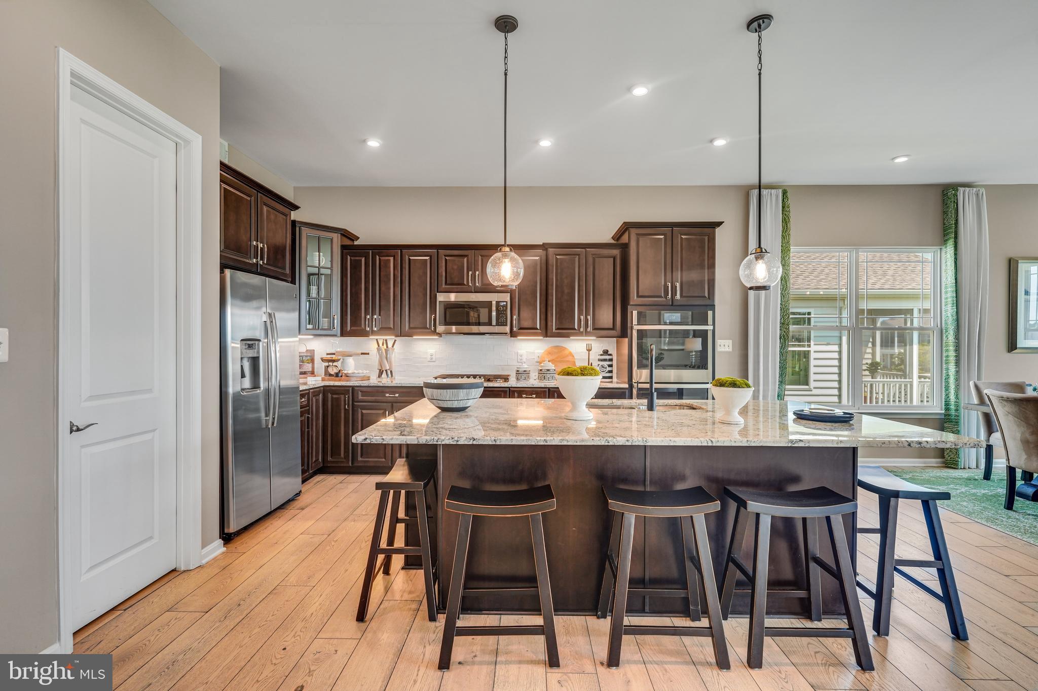 772 Honey Locust Road Middletown, DE 19709 - Photo 5 of 18 a kitchen with stainless steel appliances granite countertop a kitchen island a stove a refrigerator a sink a dining table and chairs with wooden floor