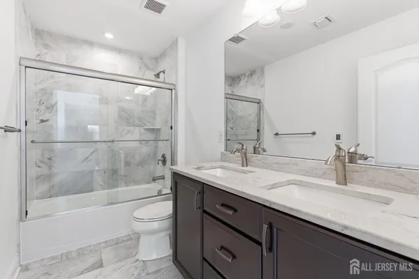a bathroom with a granite countertop sink toilet and shower