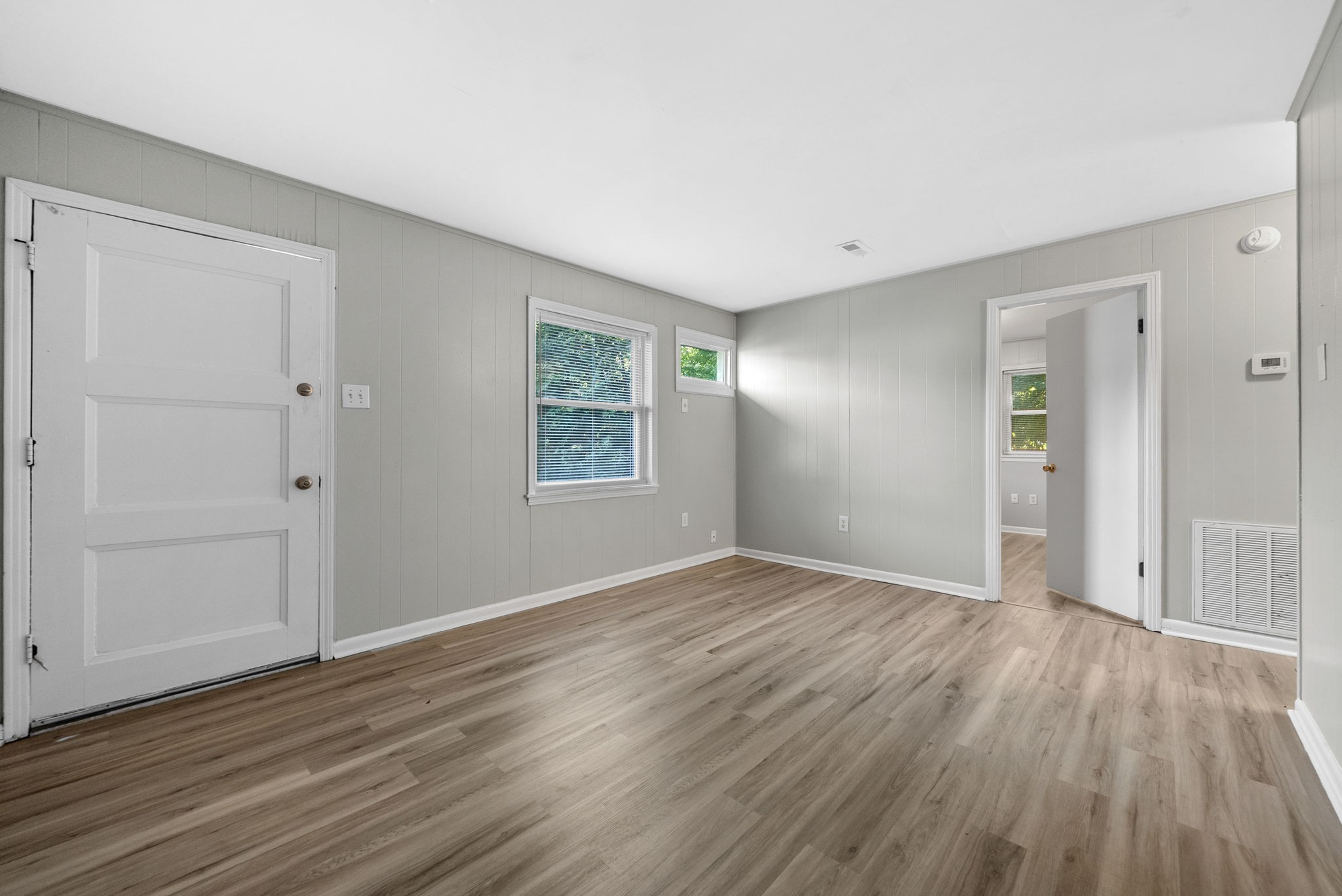 an empty room with wooden floor and windows
