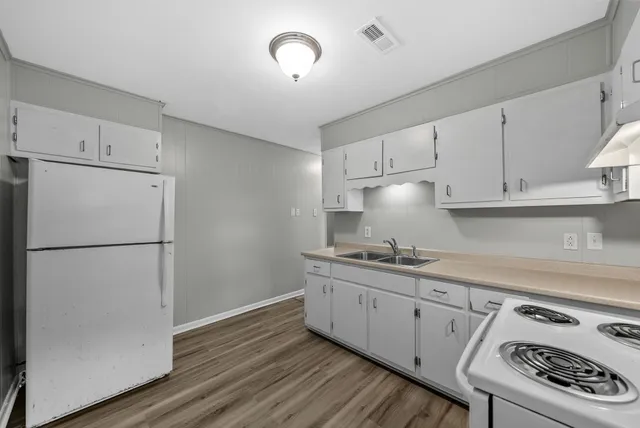 a kitchen with a sink a refrigerator and cabinets