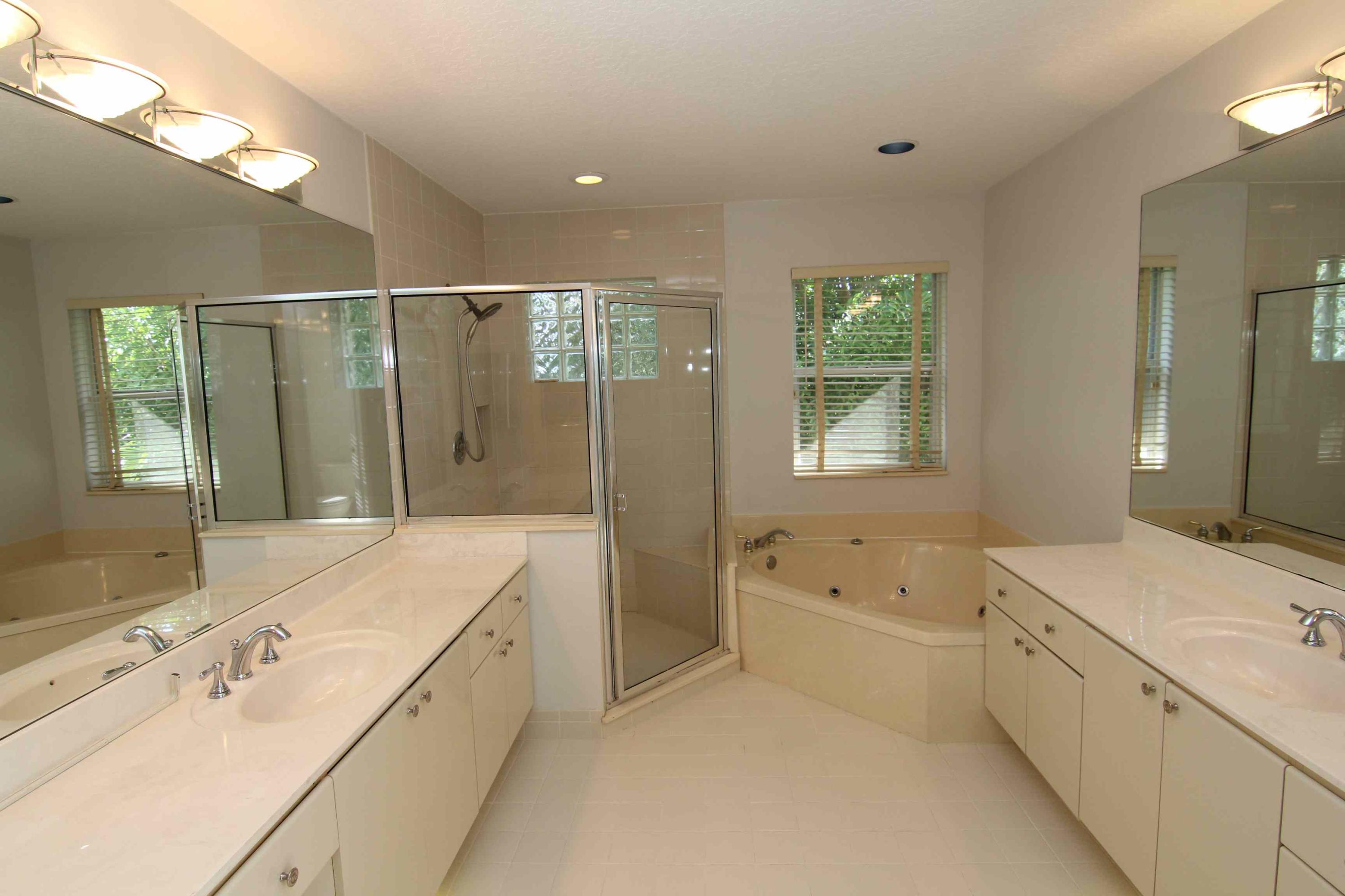 18540 Ocean Mist Drive Boca Raton, FL 33498 - Photo 16 of 37 a spacious bathroom with a double vanity sink a large mirror and a bathtub with shower