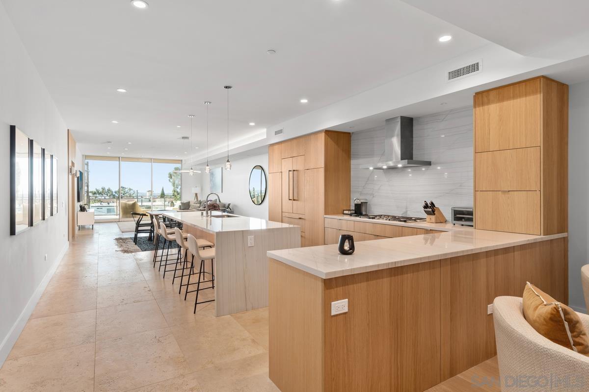 a view of a kitchen with kitchen island stainless steel appliances a sink and living room view