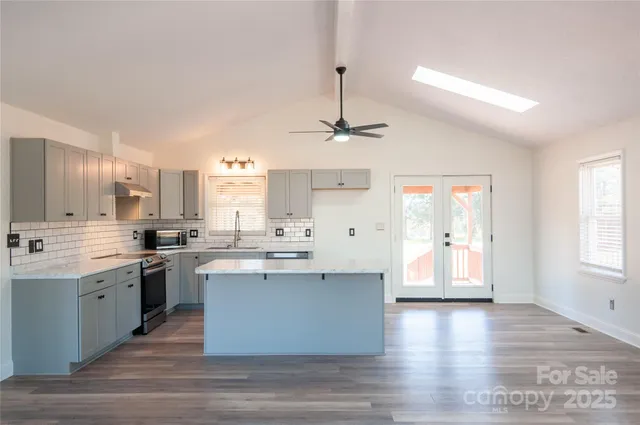a kitchen with stainless steel appliances a sink cabinets and wooden floor
