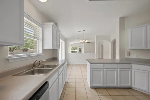 a kitchen with a sink dishwasher a stove and white cabinets with wooden floor