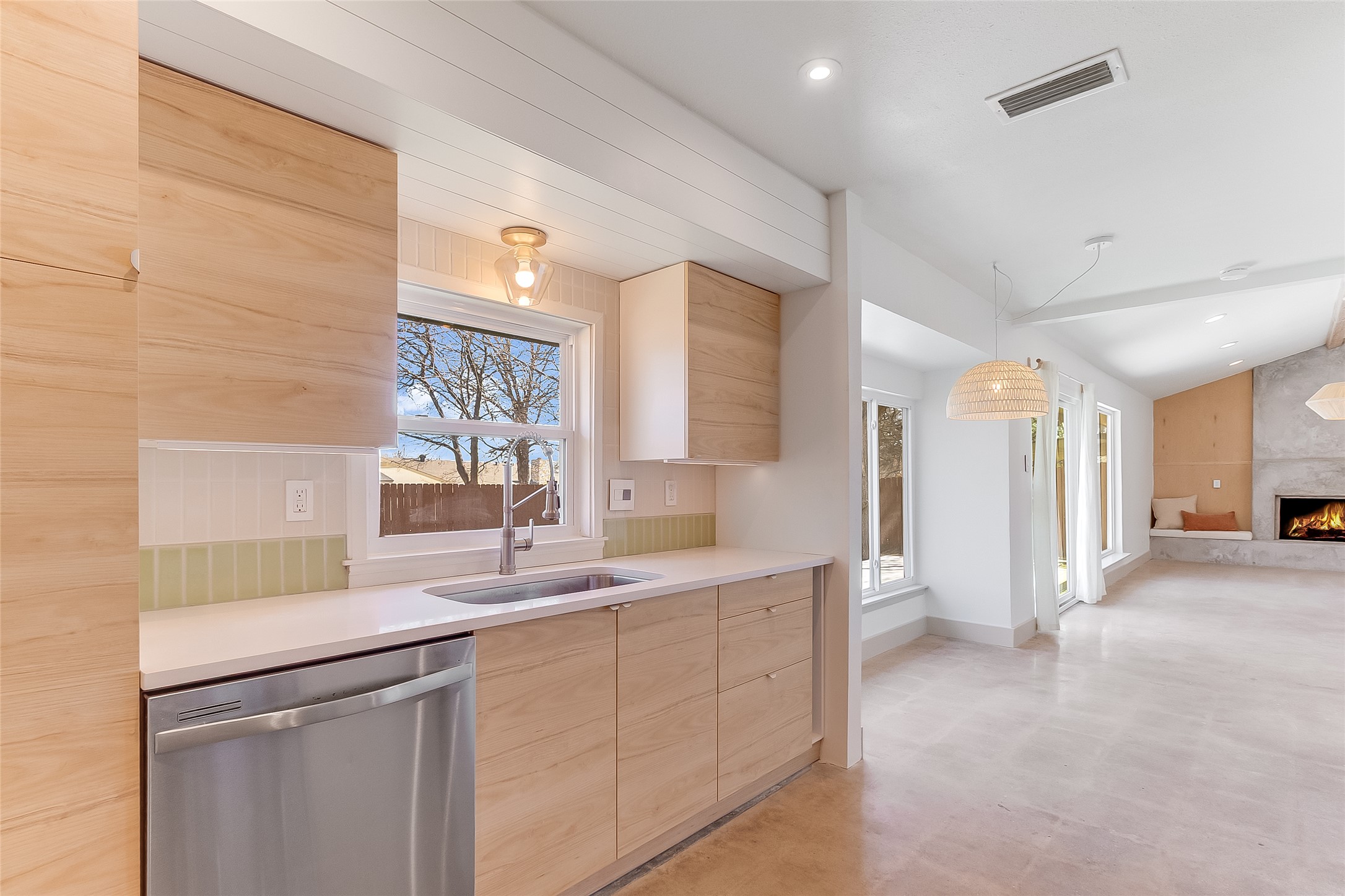 10101 Rutland Village East Austin, TX 78758 - Photo 10 of 26 Kitchen with modern light wood cabinets, two-tone ceramic tile backsplash, stainless steel dishwasher, and window above the Kraus sink.