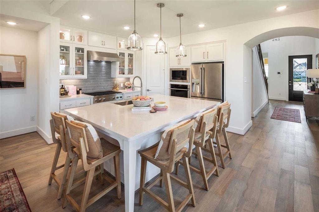a kitchen with stainless steel appliances kitchen island granite countertop a dining table chairs and wooden floor