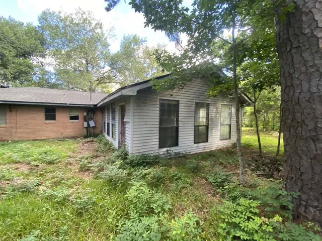 a view of a house with a small yard plants and large tree