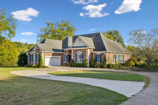 a view of a house with a big yard and large trees