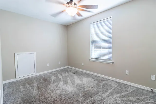 an empty room with a ceiling fan and a window