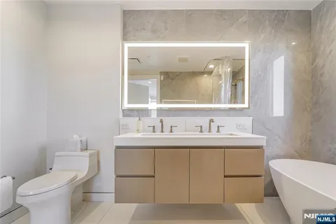 a bathroom with a toilet a sink a tub and mirror