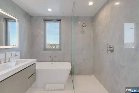 a bathroom with a bathtub shower sink and mirror