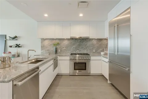 a kitchen with stainless steel appliances granite countertop a sink and a refrigerator