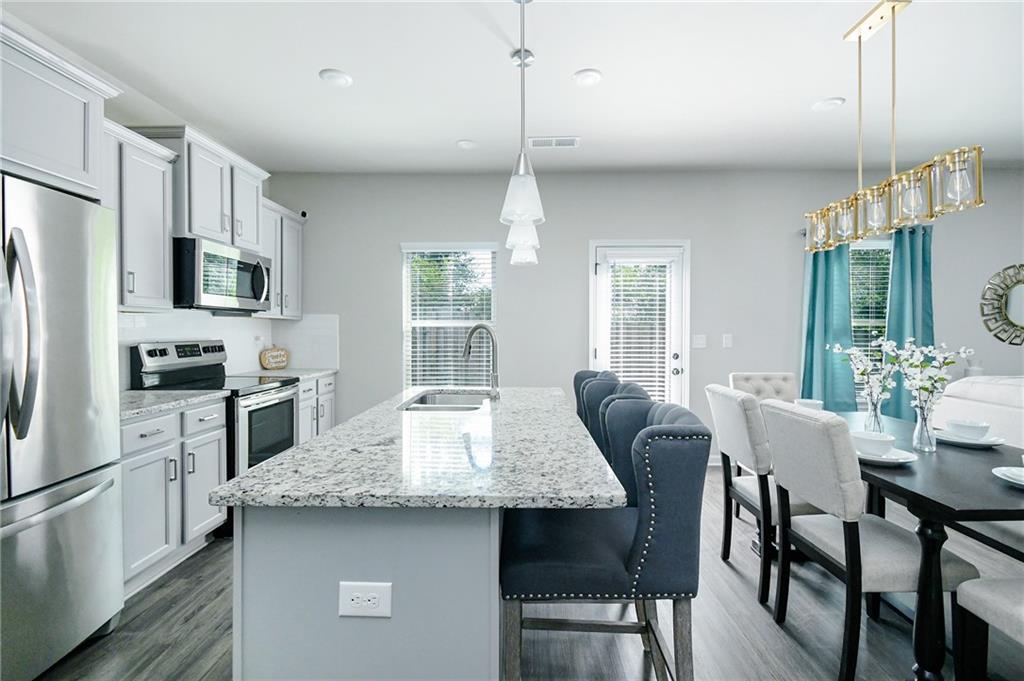 2288 Elsie Way Hampton, GA 30228 - Photo 11 of 45 a kitchen with granite countertop a table chairs microwave and refrigerator