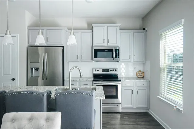 a kitchen with stainless steel appliances granite countertop a sink stove microwave and refrigerator