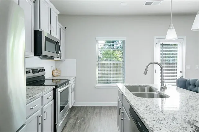 a kitchen with kitchen island granite countertop a sink a stove and a chandelier