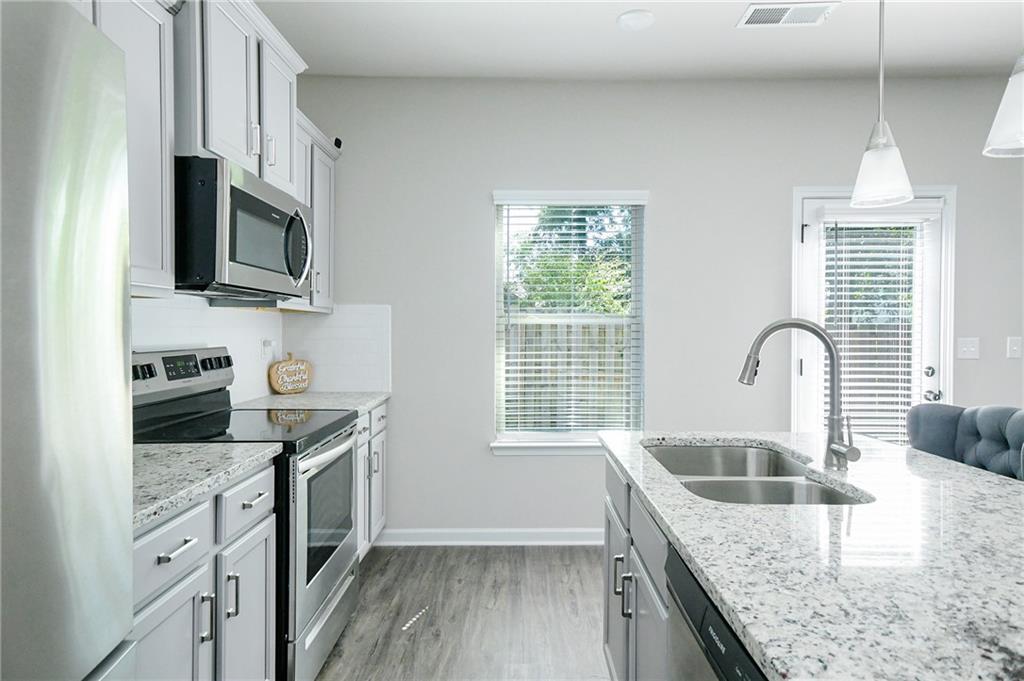 2288 Elsie Way Hampton, GA 30228 - Photo 13 of 45 a kitchen with stainless steel appliances granite countertop a sink stove microwave and refrigerator
