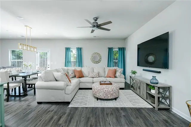 a living room with furniture kitchen view and a large window