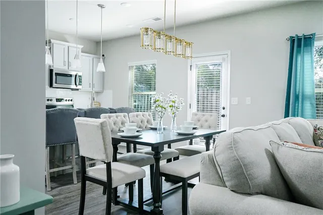 a kitchen with stainless steel appliances granite countertop a refrigerator a sink a stove a dining table and chairs