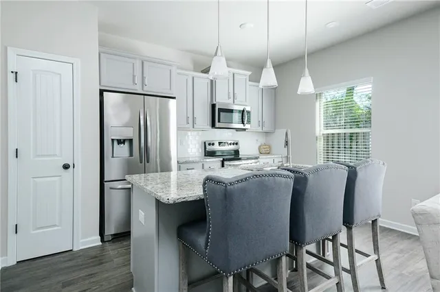 a kitchen with granite countertop a table chairs microwave and refrigerator