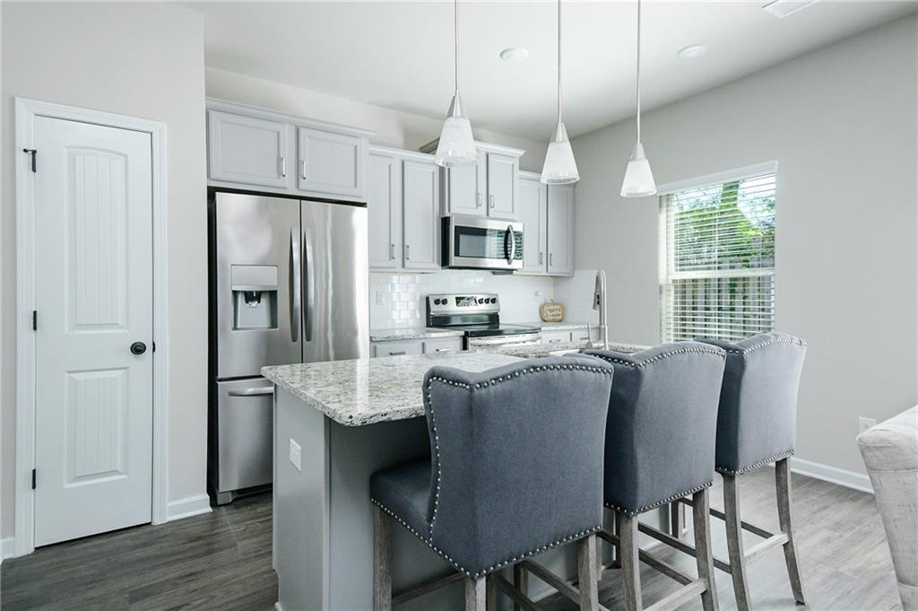 2288 Elsie Way Hampton, GA 30228 - Photo 10 of 45 a kitchen with stainless steel appliances granite countertop a refrigerator a sink a stove a dining table and chairs