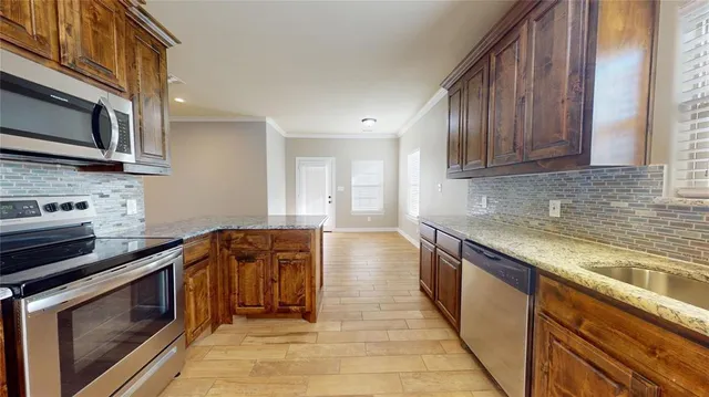 a kitchen with stainless steel appliances granite countertop a stove a sink and a microwave