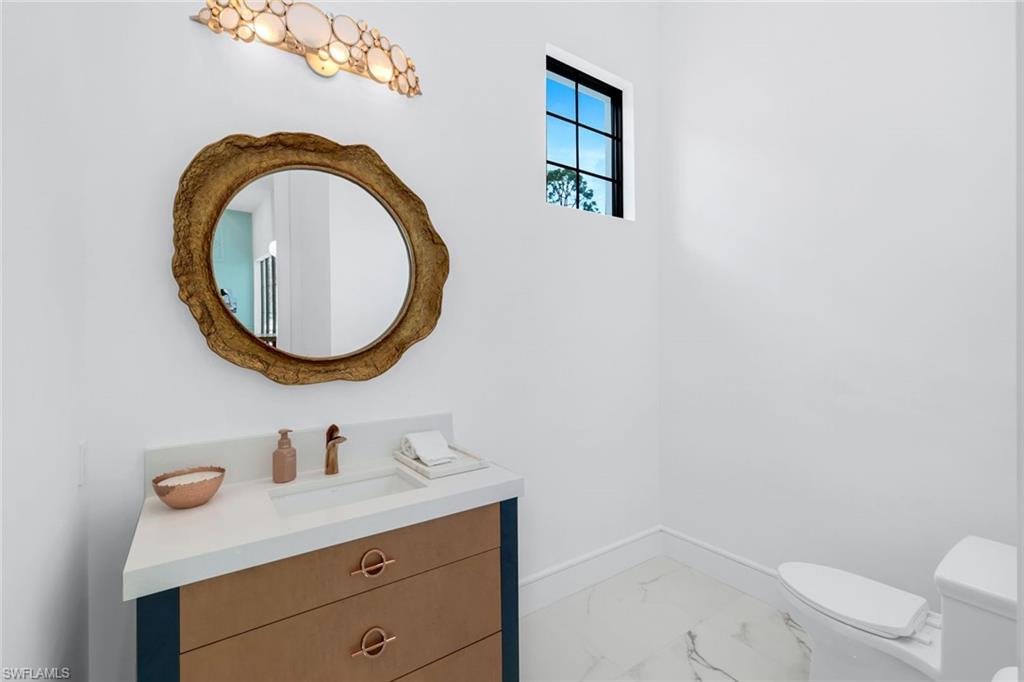 6677 Hunters Road Naples, FL 34109 - Photo 23 of 50 a bathroom with a sink a mirror and a toilet