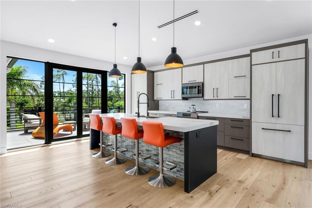 6677 Hunters Road Naples, FL 34109 - Photo 34 of 50 a kitchen with stainless steel appliances granite countertop a stove a sink and a refrigerator with wooden floor