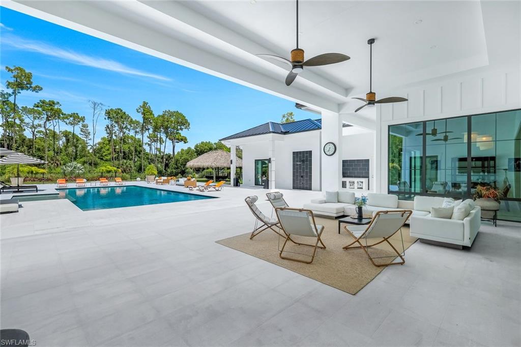 6677 Hunters Road Naples, FL 34109 - Photo 40 of 50 a living room with patio furniture and a floor to ceiling window
